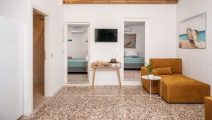 A compact living space with a kitchenette, a TV mounted on the wall, a small table with a plant, and a sofa. - Seaside Villa Angel - Samos Cozy Getaway (Samos)