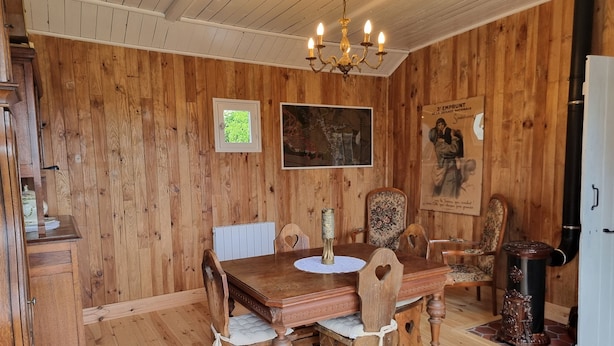 A wooden-paneled room with a dining table, chairs, a chandelier, and a vintage stove. - La Germaine - wooden shack in the countryside (Ribécourt-Dreslincourt)