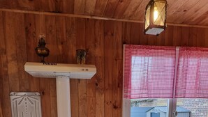 A wooden cabin interior with a kitchenette, including a stove, oven, and a window with checkered curtains. - La Germaine - wooden shack in the countryside (Ribécourt-Dreslincourt)