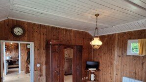 A wooden-paneled room with a bed, a wooden cabinet, a clock, a lamp, and a window with curtains. - La Germaine - wooden shack in the countryside (Ribécourt-Dreslincourt)