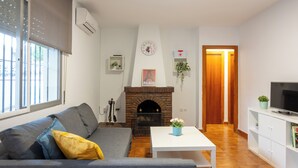 Ein Wohnzimmer mit Sofa, Tisch, Kamin, Fernseher und einer Tür zu einem anderen Raum.