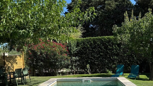 A rectangular swimming pool with clear water, surrounded by a stone deck and a grassy area. - Country House (Caumont-sur-Durance)