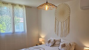 A bedroom with a large bed, a hanging macrame wall decoration, and a window with curtains. - Country House (Caumont-sur-Durance)