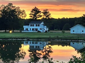 A large white house with a porch, a small barn, and a calm lake reflecting the sky. - Beautiful 3-bedroom Miles River waterfront in tranquil Easton - Relax and unwind (Easton)