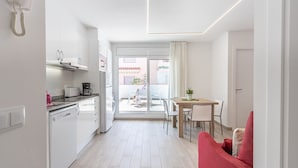 Une cuisine moderne avec des meubles blancs, une machine à café et un coin repas comprenant une table et des chaises.