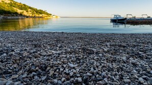 A pebbled beach with boats docked on the right.