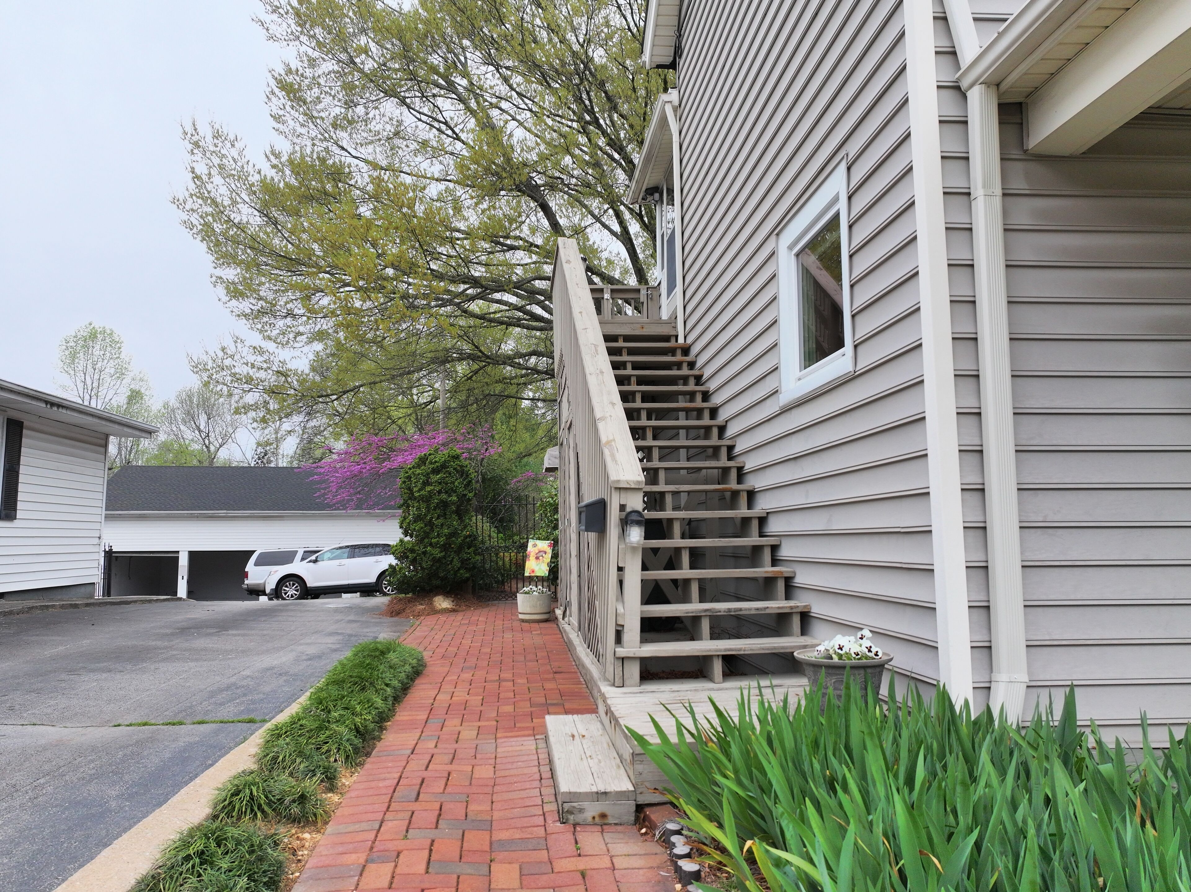 A residential property with a garage, a staircase leading to the entrance, and a brick pathway.