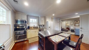 Een ruime keuken met moderne apparatuur, een eethoek met een tafel, en een gezellige woonkamer met een bank en een open haard.