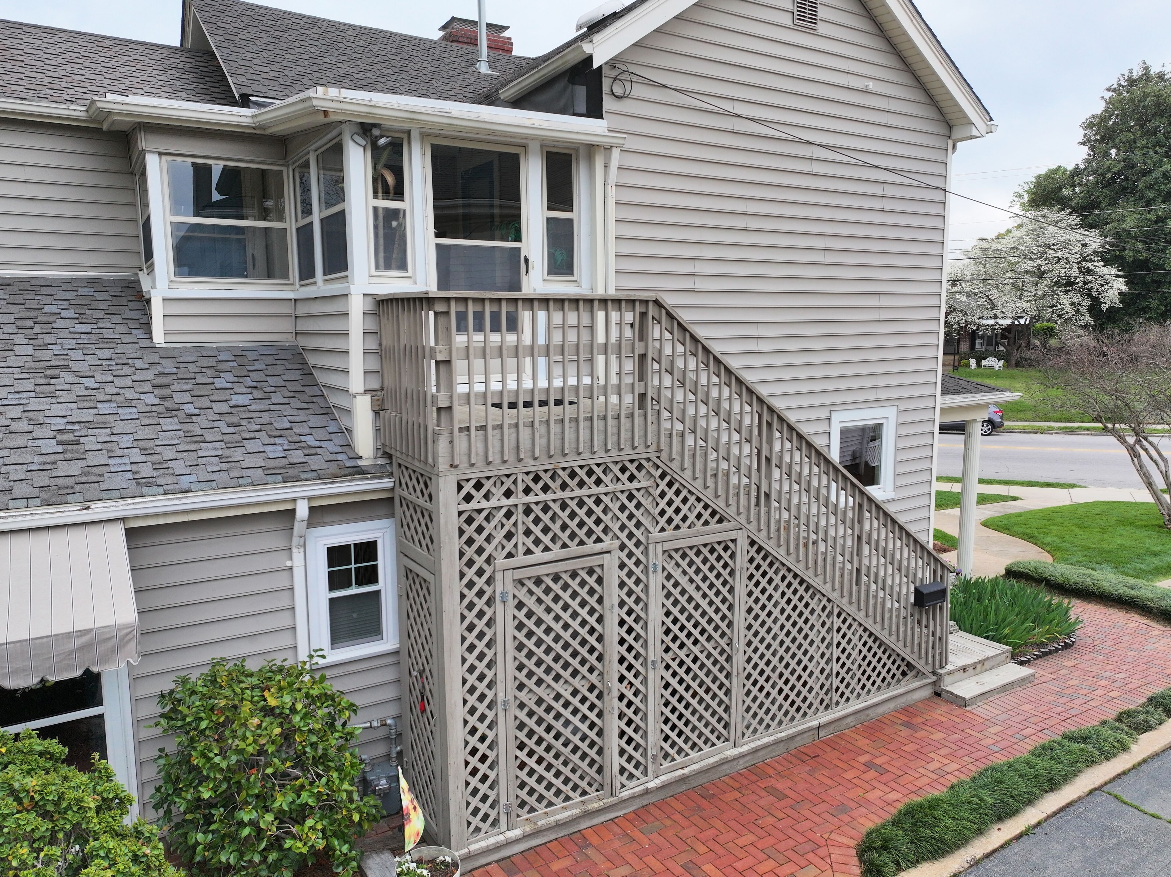A two-story house with a wooden deck and a covered front porch.