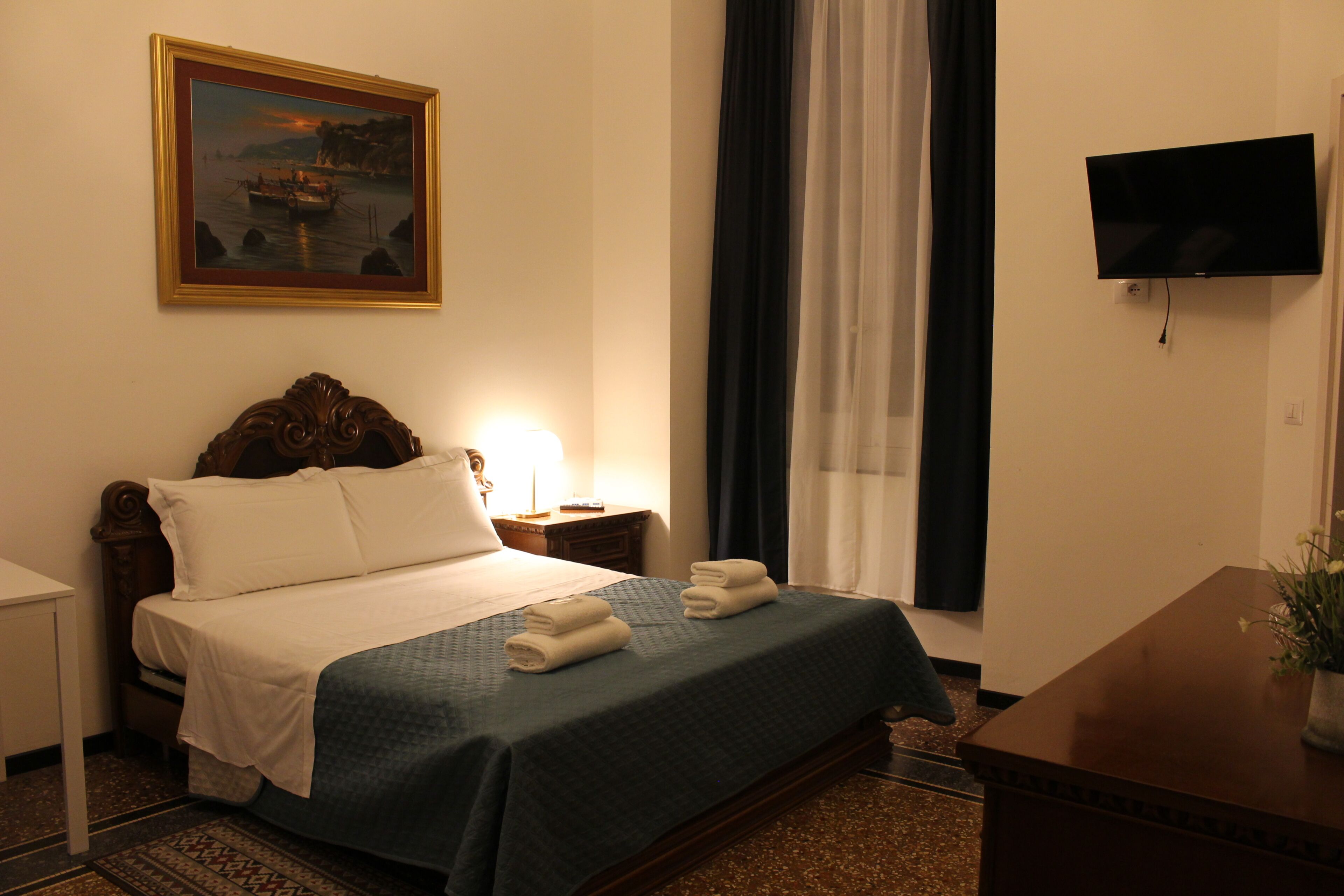 Ein Hotelzimmer mit einem Bett, einem Nachttisch, einem Fernseher und einem Bild an der Wand.