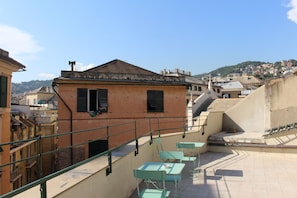 Terraza en la azotea con mobiliario exterior y vistas a un pueblo en la colina.