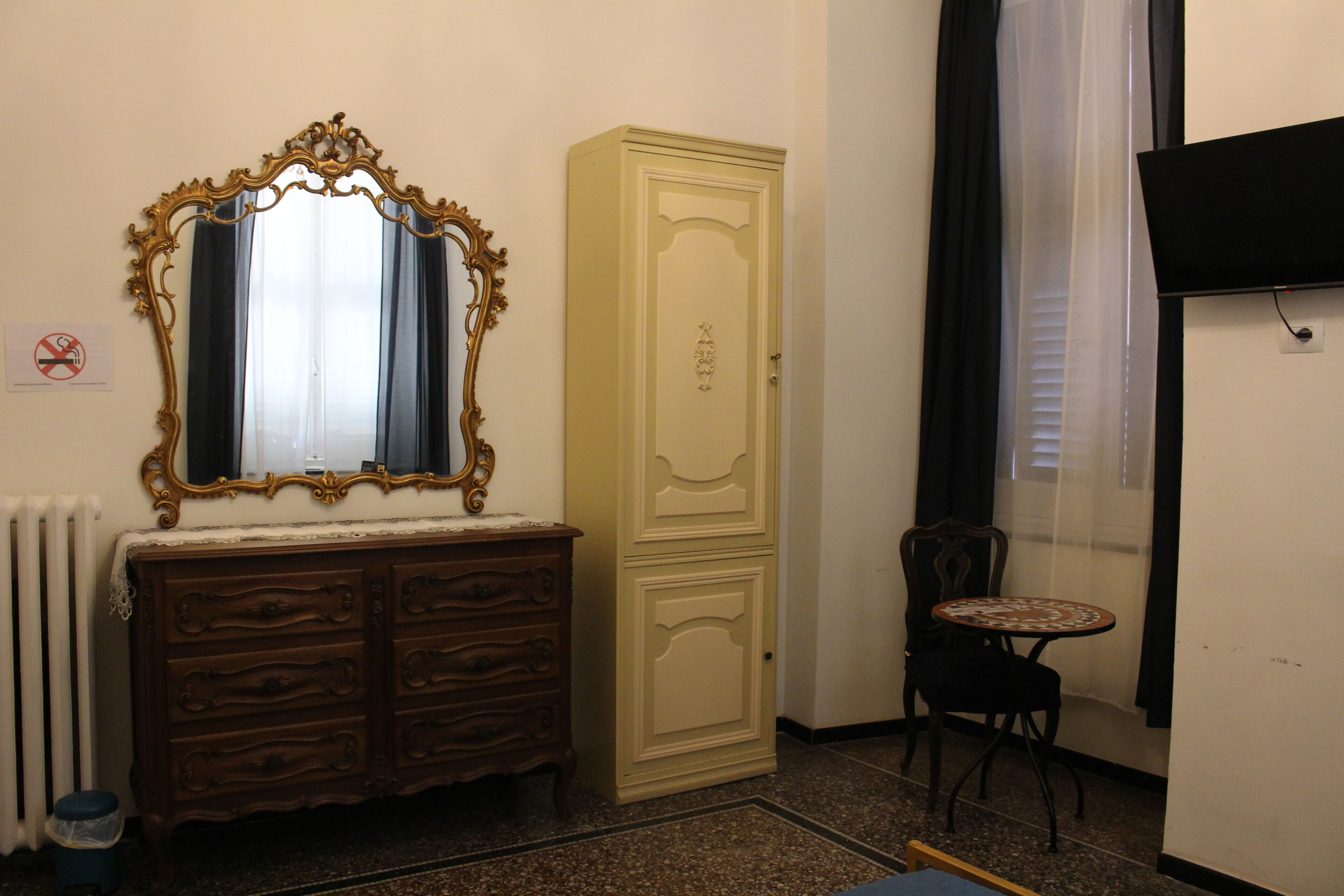 A room with a wooden dresser, a tall cabinet, a small round table, and a radiator.