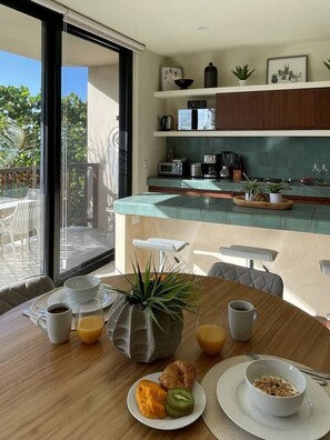 Ett modernt kök med en frukosthörna, inklusive ett bord med kaffe, juice och en croissant, samt en balkong med utemöbler.