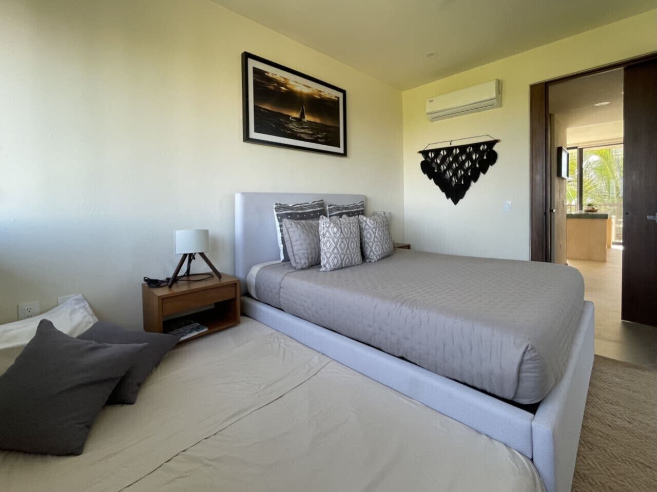 A bedroom with a bed, bedside table, lamp, and a framed picture on the wall.