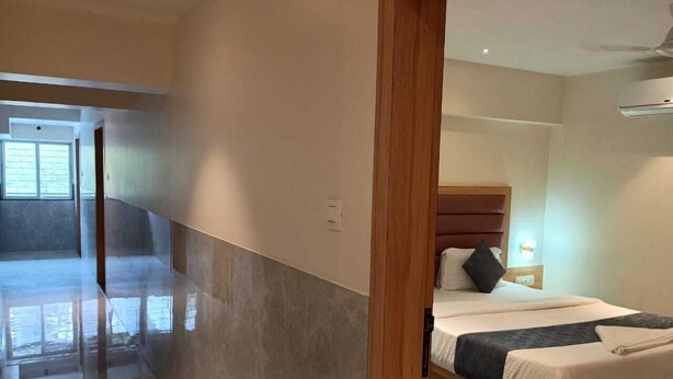 Une chambre d’hôtel moderne avec un grand lit, une tête de lit en bois et une table de chevet avec une lampe.