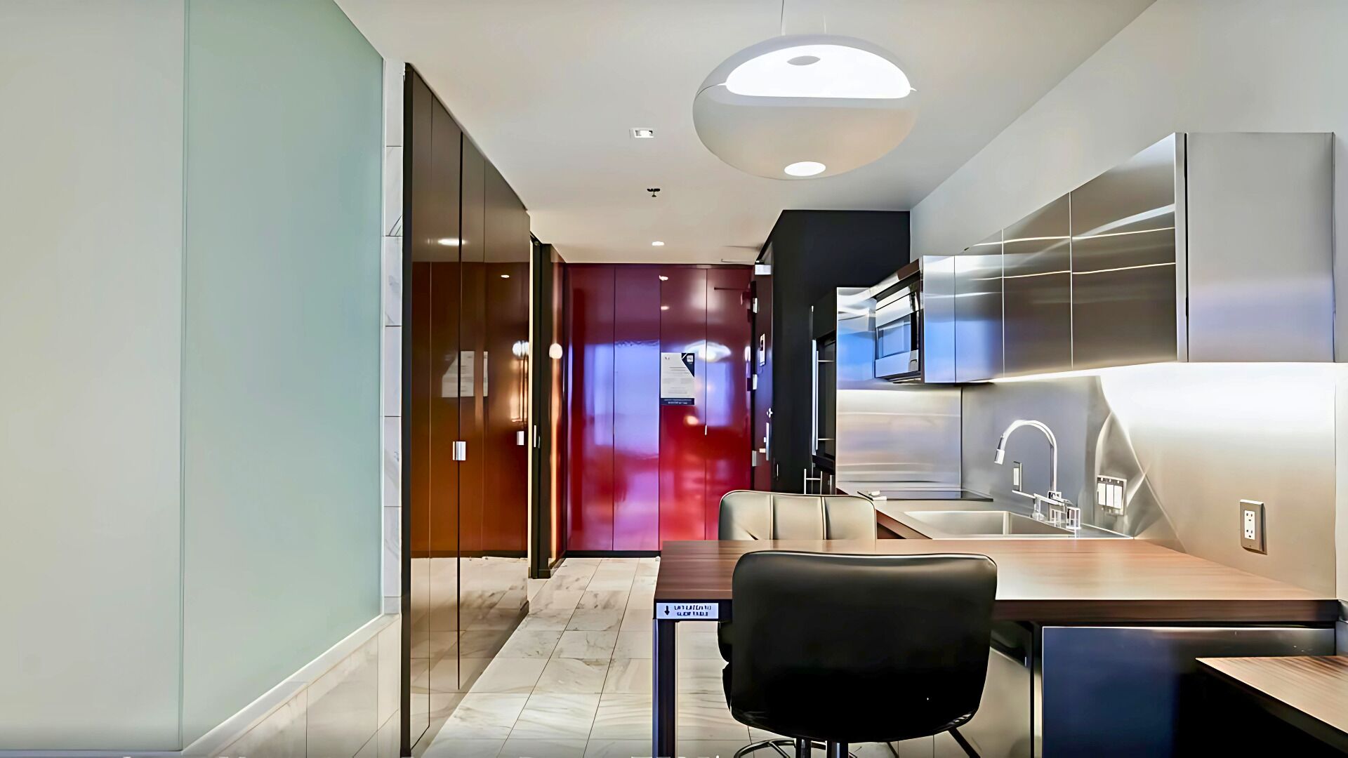 A modern kitchen with a built-in oven, a sink, and a dining area with a table and chairs.