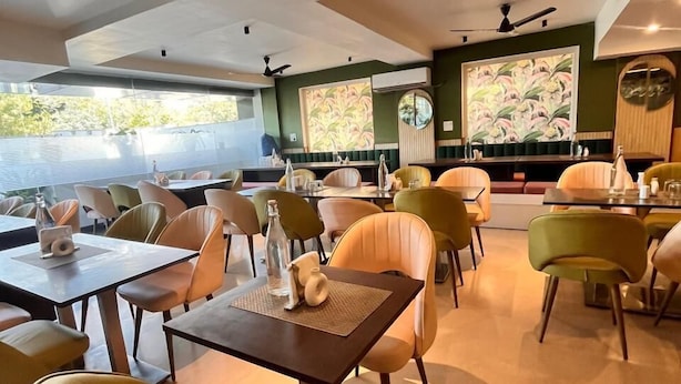 A restaurant with modern furniture, large windows, and a view of the outdoors. - Pink Guava  (Gurugram)