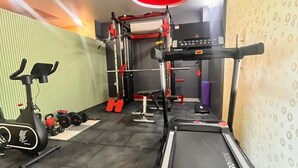 A gym with a treadmill, exercise bike, and weightlifting equipment. - Pink Guava  (Gurugram)