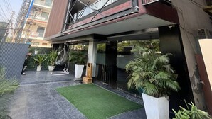 A modern building with a multi-story structure, a covered entrance, and a landscaped courtyard with potted plants. - Pink Guava  (Gurugram)