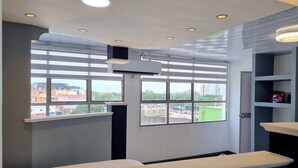Habitación de hotel con un ventanal grande, una recepción blanca y vistas a la ciudad.