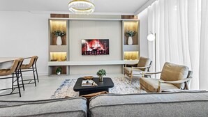 A modern living room with a flat-screen TV, comfortable seating, a coffee table, and decorative plants.