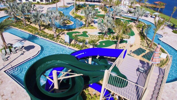 A resort with a large water slide, multiple pools, and a golf course.