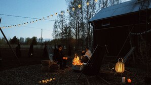 An outdoor setting with a fire pit, string lights, and a lantern.
