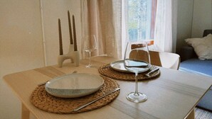 Et spisebord dækket med tallerkener, bestik og vinglas, med udsigt til en skov gennem et vindue.