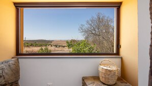 A window with a view of a rural landscape, a stone ledge, and a wicker basket.