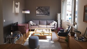 A living room with a sofa, coffee table, ottoman, and a bookshelf.