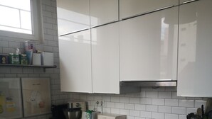 A modern kitchen with white cabinets, a stainless steel oven, a coffee maker, and a toaster.