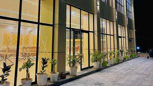 A modern building with large windows and a row of potted plants along the front. - Rana Ji Haveli (Najibabad)