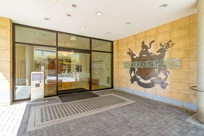 A hotel entrance with a glass door, a reception desk, and a wall-mounted sign. - Elegant Retreat with Balcony & BBQ (Victoria)