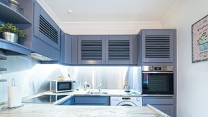 A compact kitchen with a microwave, oven, and washing machine.
