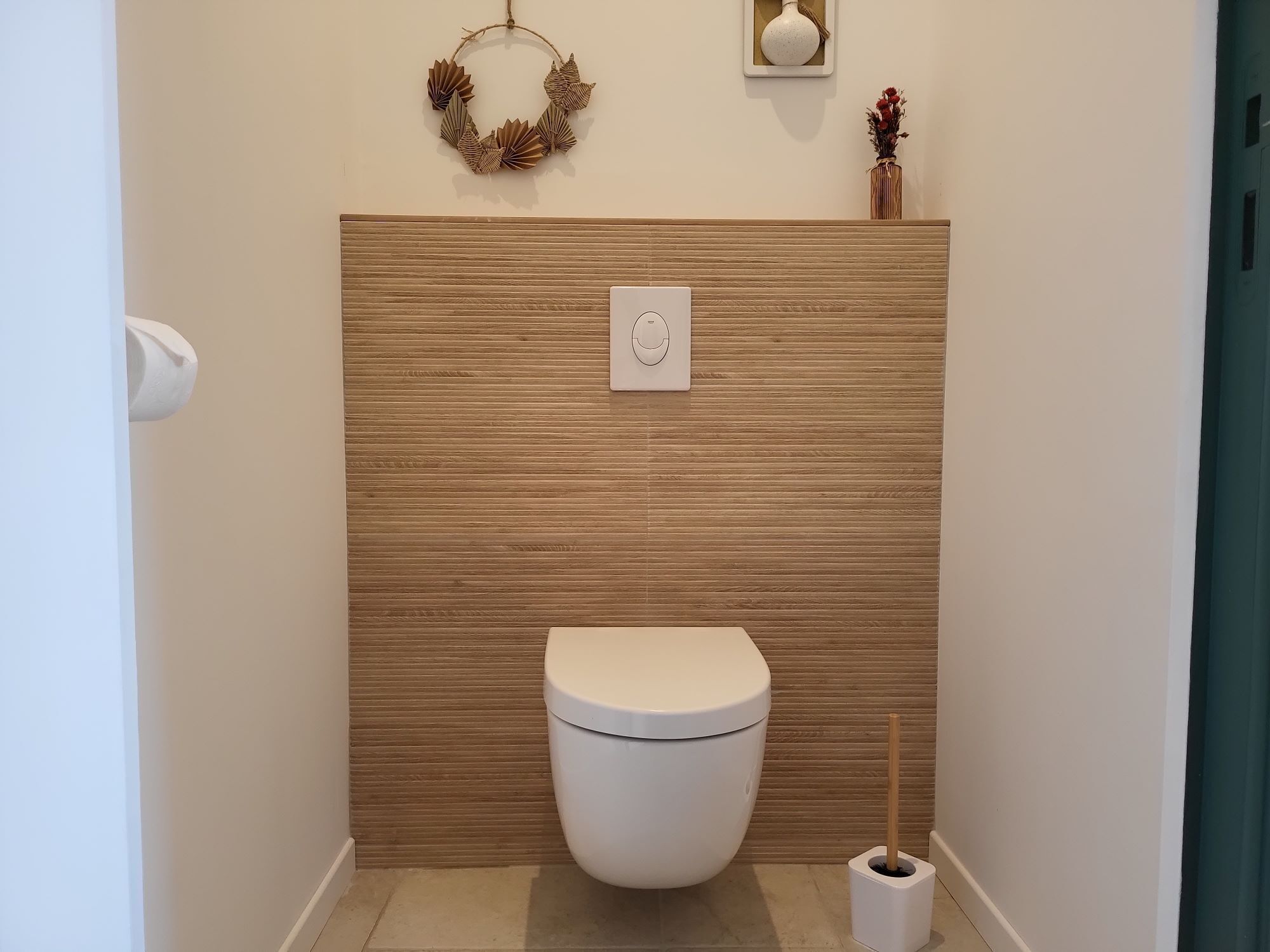 A modern bathroom with a toilet, a wall-mounted flush handle, and a toilet brush.