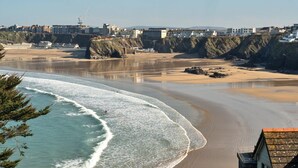 A coastal view with a beach, cliffs, and buildings in the background. - Apartment in Cornwall with Towan Beach Views (Newquay)