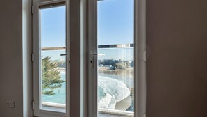 A room with a view of a beach and a cityscape through a window. - Apartment in Cornwall with Towan Beach Views (Newquay)