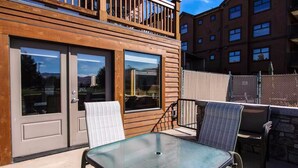 A wooden building with a balcony, a glass door, and a table with chairs.