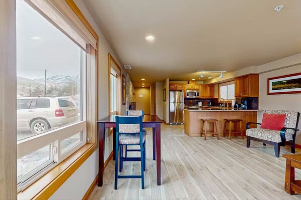 A spacious kitchen with wooden cabinets, a central island, and a dining area with a table and chairs.