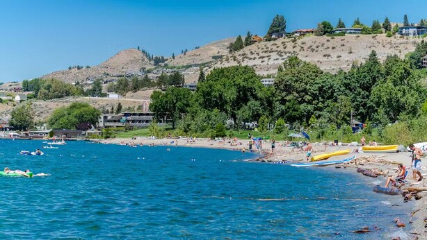 A coastal beach with clear blue water, boats, and people enjoying the beach.