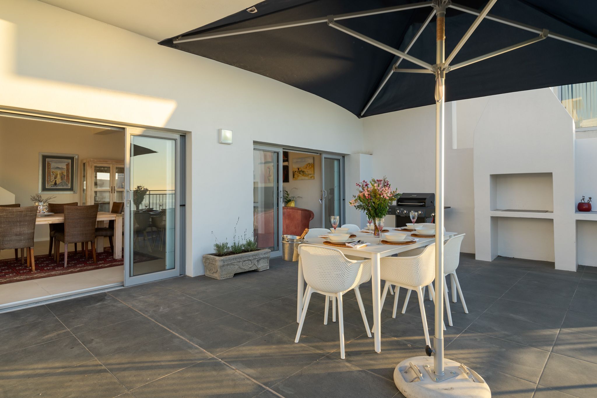 An outdoor patio with a dining table, chairs, and a large umbrella.