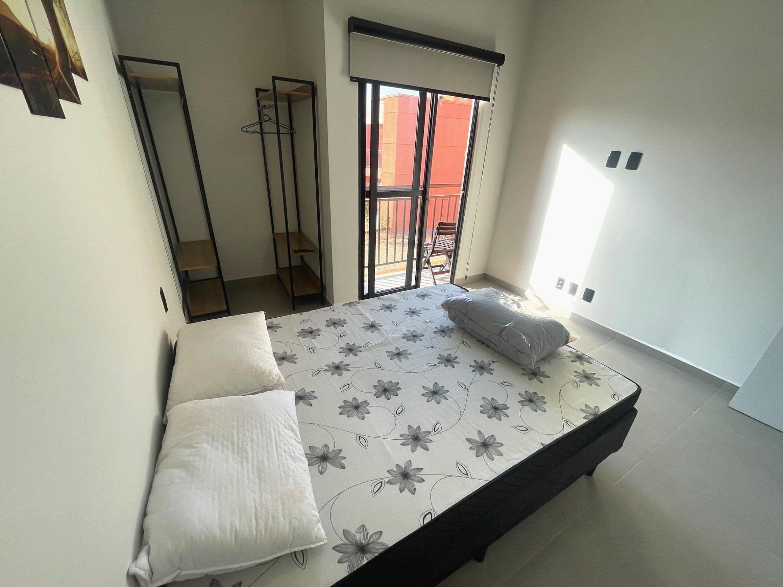 Ein Schlafzimmer mit Bett, Kleiderschrank und Balkon.