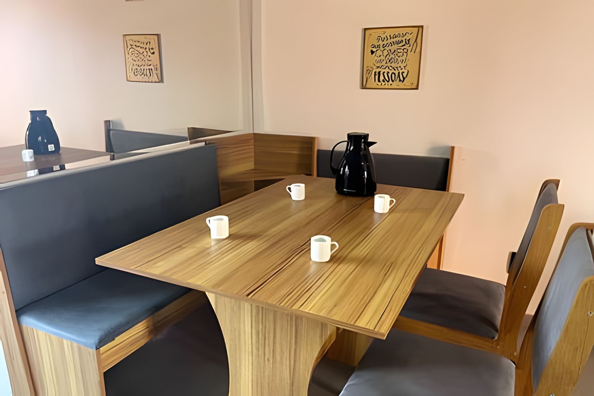 Et spiseområde med et træbord, fire stole og en kaffekande.