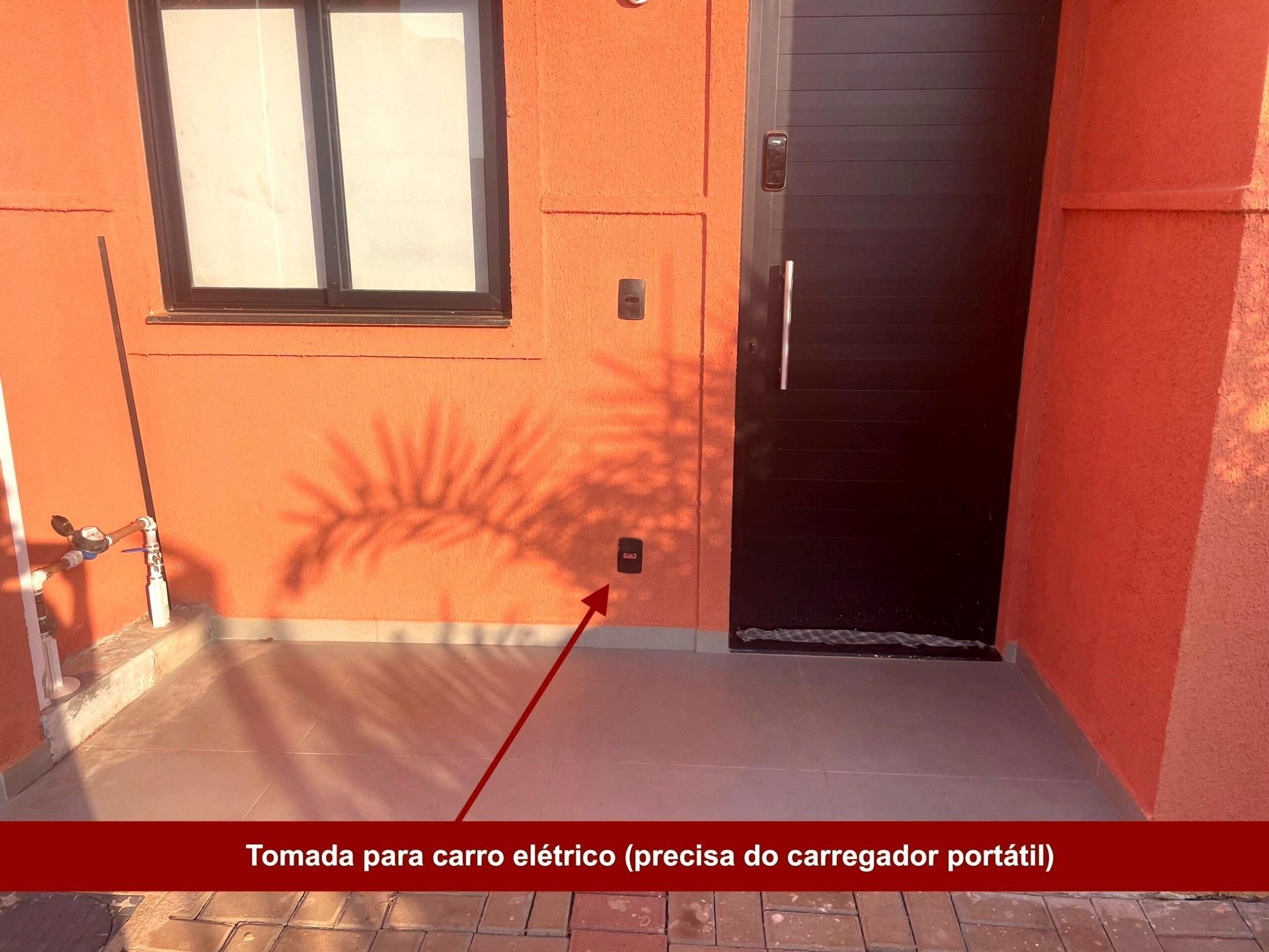Un corridoio esterno stretto con pavimento piastrellato, una porta e una finestra che proietta un'ombra.