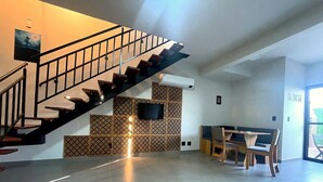 A modern interior with a staircase, a dining area, and a wall-mounted TV.