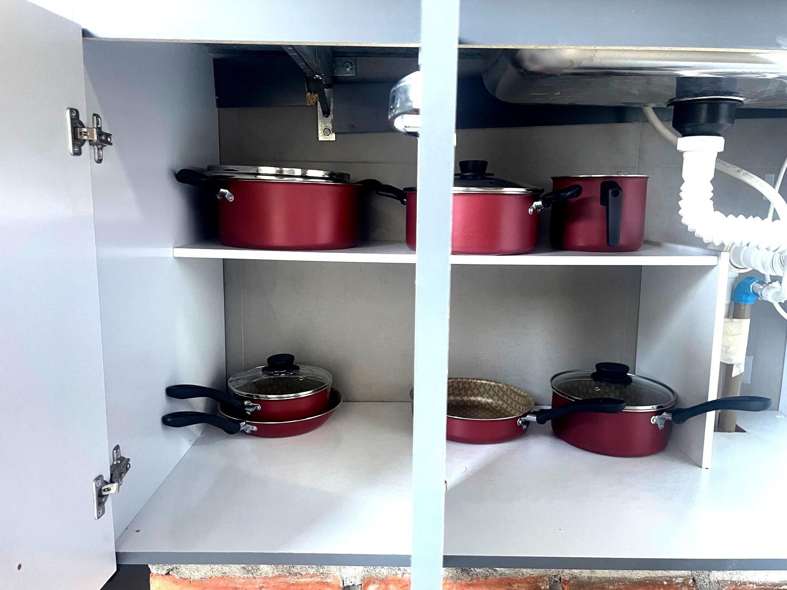 A kitchen with white cabinets, red pots, and a water dispenser.