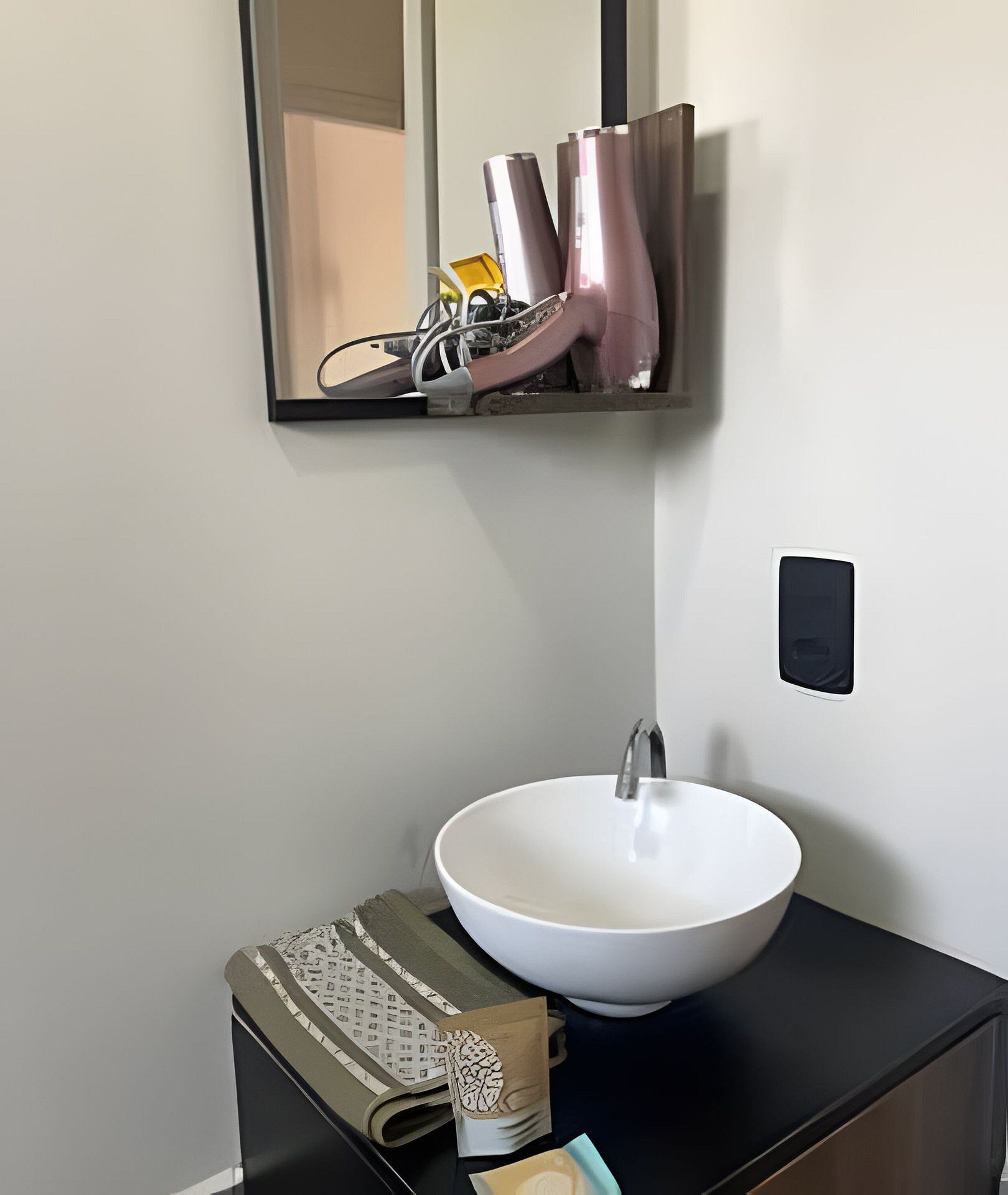 A bathroom with a white sink, a mirror, and a black countertop.
