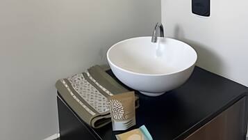 A bathroom with a white sink, a mirror, and a black countertop.