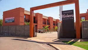 A modern building with a sign for 'Casas Duplex Venda e Locação' and 'Condomínio Riviera Premium'.
