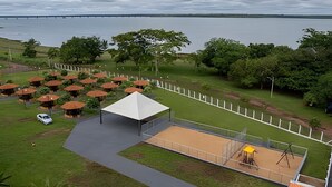 An outdoor seating area with umbrellas, a covered seating area, and a view of a body of water.